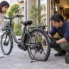パンクした電動自転車の後輪を自転車店で確認する整備士