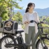 犬用キャリーに入った小型犬と、そばに立つ飼い主の電動自転車