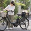 日用品を安定して積んだ電動自転車と荷物を確認する人