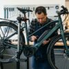 自転車プロショップで整備スタンドに載せられた電動アシスト自転車のバッテリーや駆動系を点検する様子